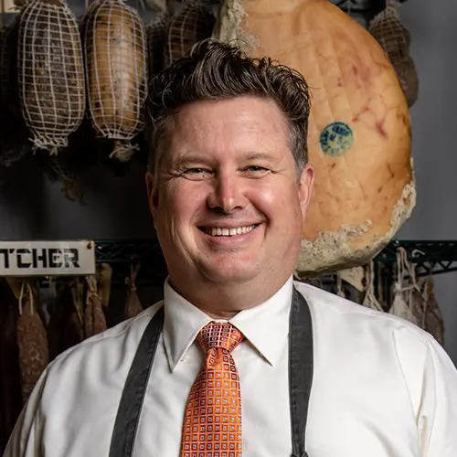 Portrait of Stephen Stryjewski against a wall of curing meats