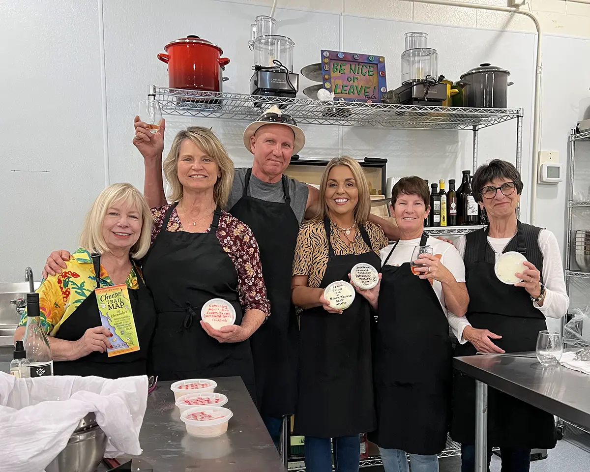 A small cheesemaking group smiles with their finished butter