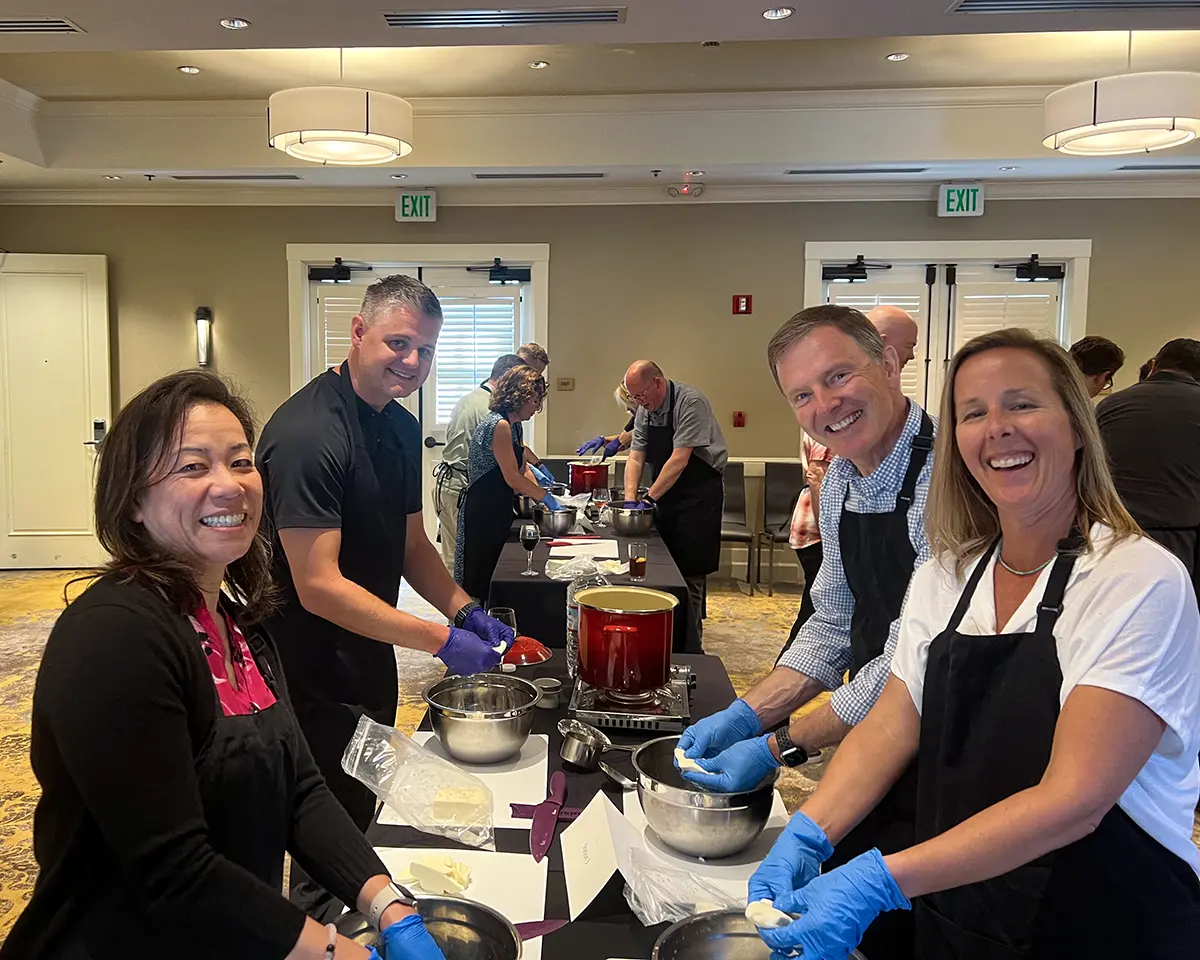 Closeup of four students making cheese in a hotel conference room