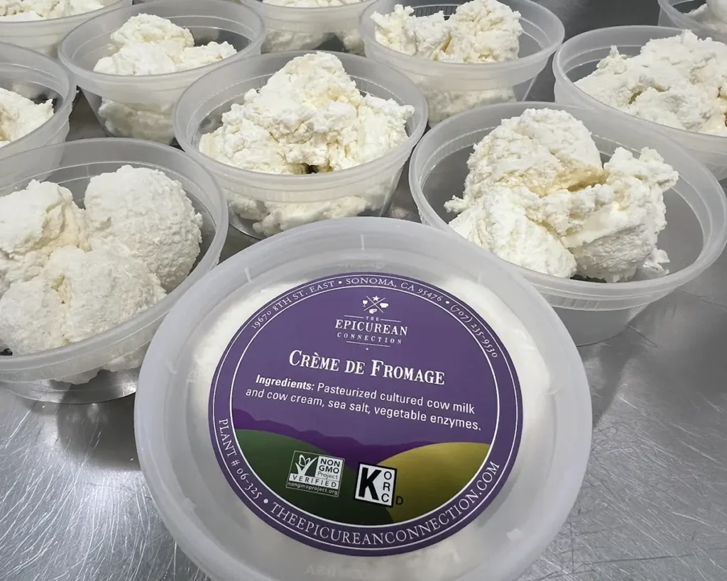 A closeup of containers of Crème de Fromage cheese being packaged for sale