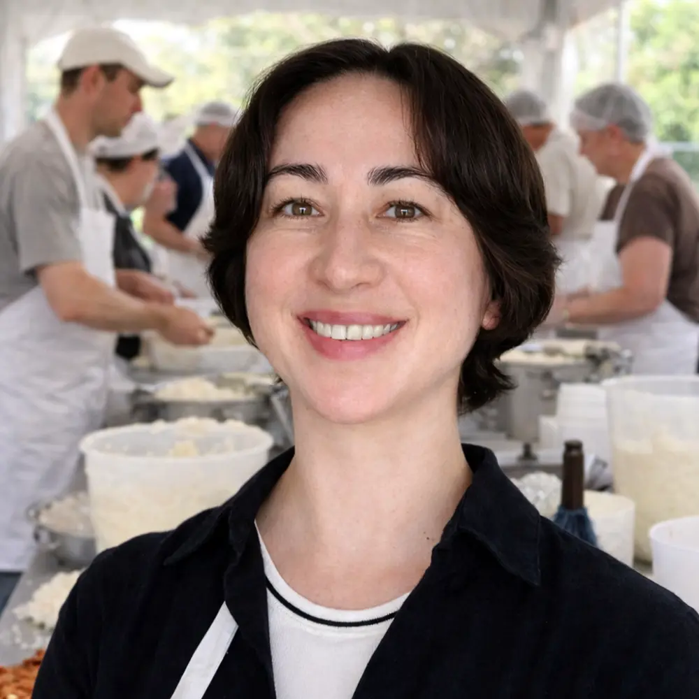 Karina Davis, wearing a white apron, smiles for a picture at a catering event