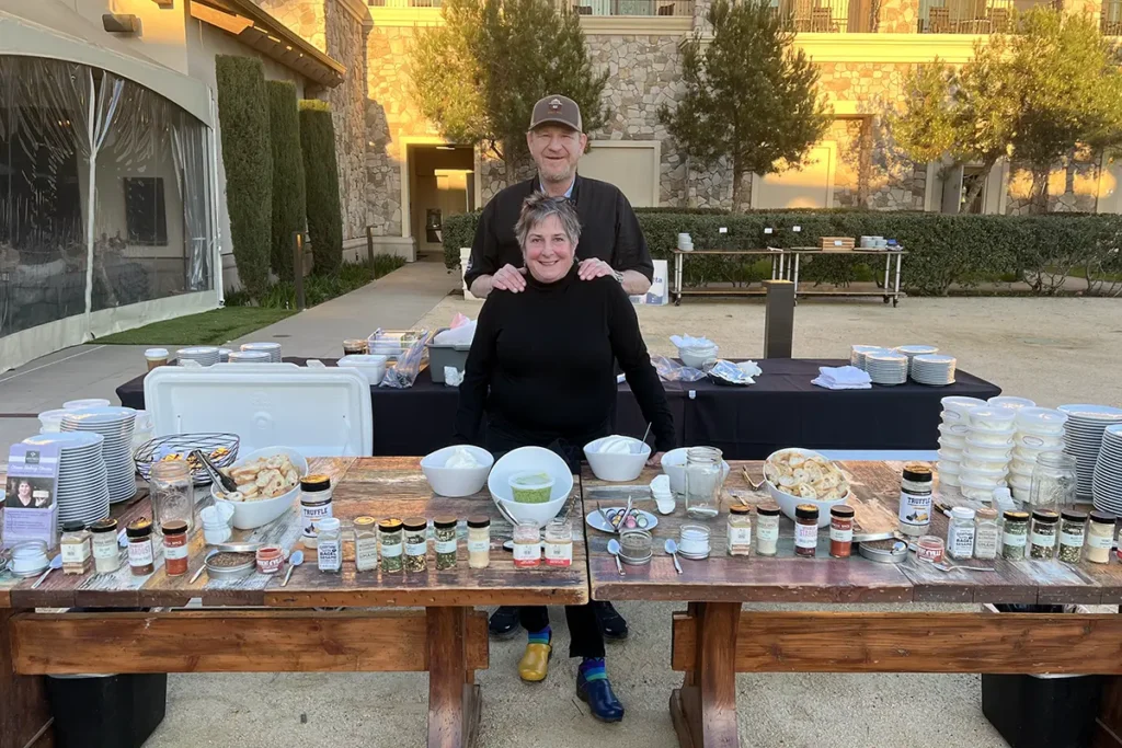 Ben Sessions and Sheana Davis stand behind a table at an outdoor catering event