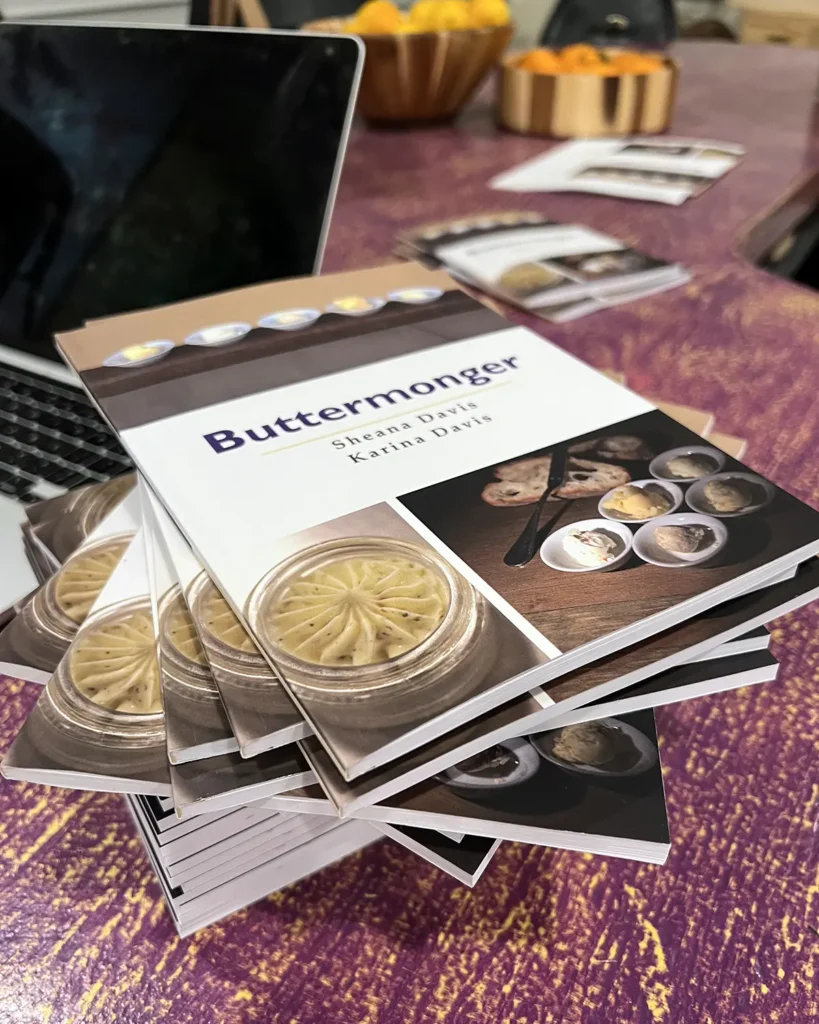 A stack of Buttermonger cookbooks on a purple table