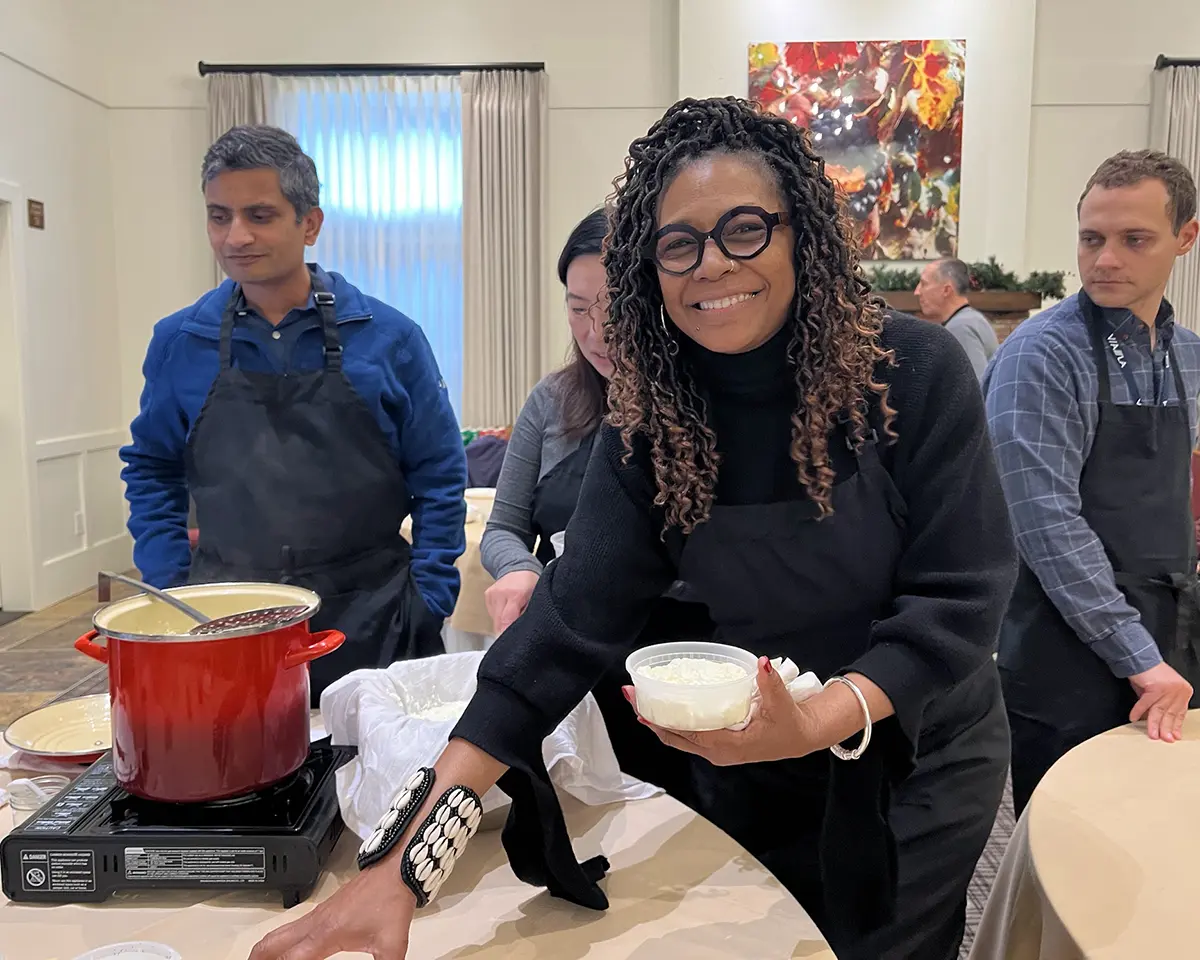 A woman smiles holding the cheese she made in class