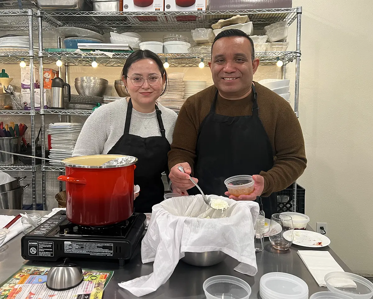 Two people making cheese during a class at the Epicurean Connection